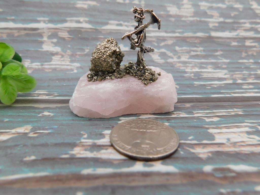 Pyrite Miner Figurine on Rose Quartz Base: Small silver-tone metal miner figure with pickaxe standing beside a pyrite cluster, mounted on a rose quartz base.