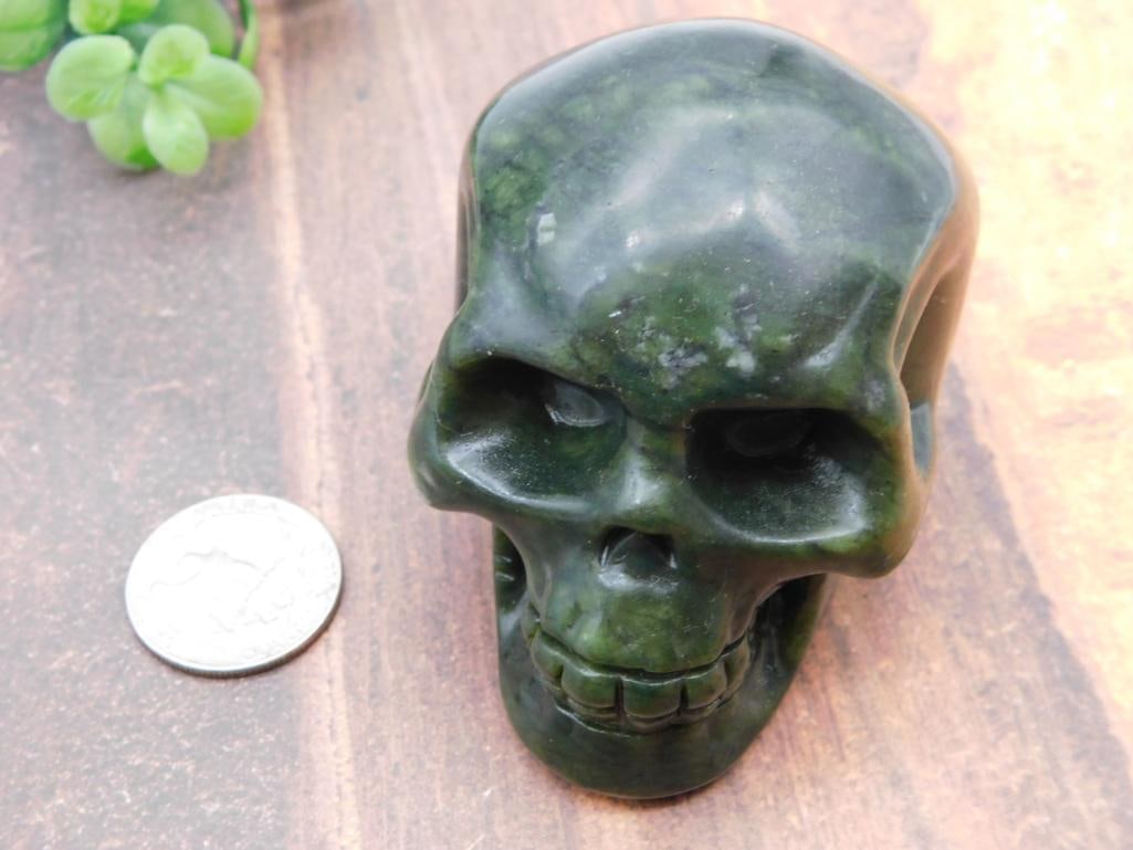 Carved Jade Skull: Detailed carved green jade skull sculpture with defined teeth and eye sockets.