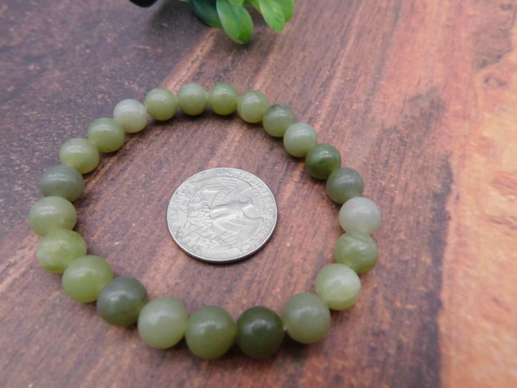 Green Jade Beaded Stretch Bracelet: Stretch bracelet of round polished jade beads in varying shades of green.