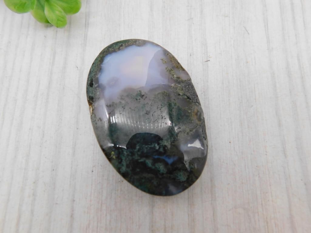 Moss Agate Cabochon Stone: Polished oval moss agate cabochon with green dendritic inclusions and translucent banding.