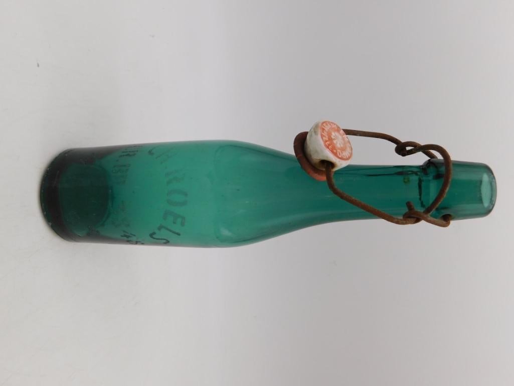 Antique Green Glass Bottle with Porcelain Stopper: Aqua-green embossed glass bottle with wire-bail porcelain stopper closure.