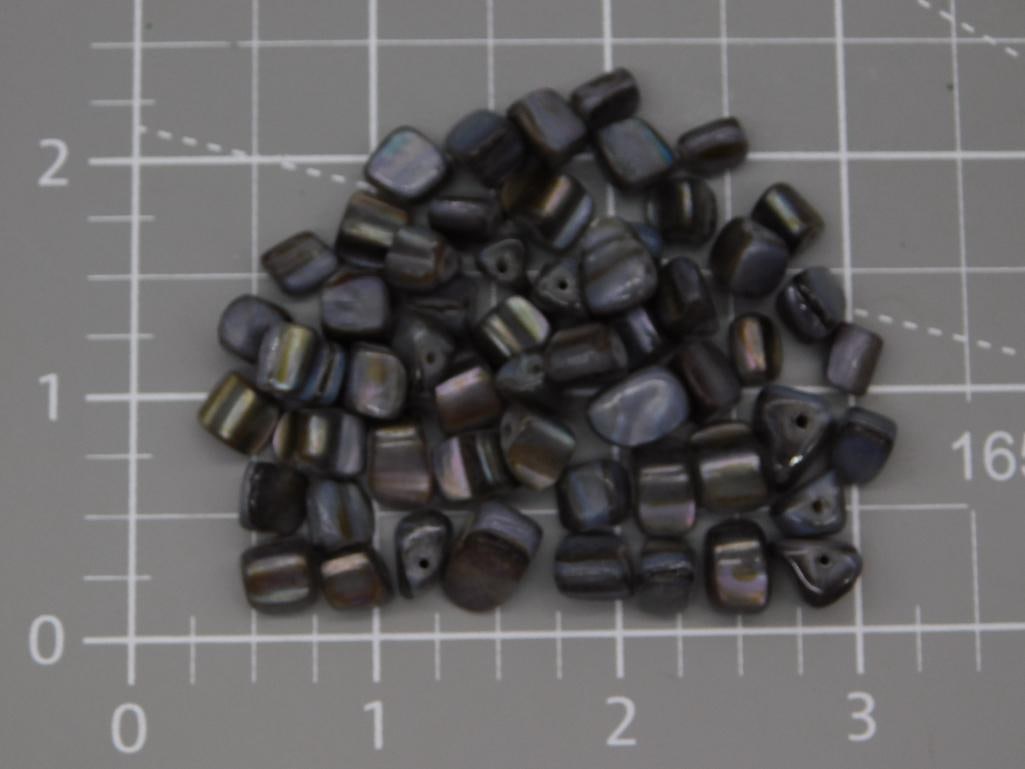 Jewelry Iridescent Shell Bead Lot for Crafting: A quantity of loose iridescent gray and bronze mother-of-pearl shell beads, drilled for stringing, in mixed rectangular and chip-cut shapes. Beads average roughly 1/2 inch, shown on a gridded mat for 
