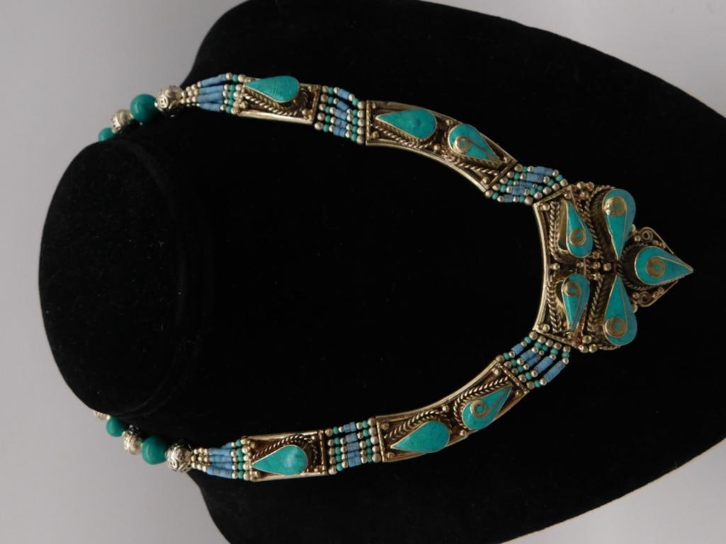 Jewelry Tibetan Silver Turquoise Statement Necklace: An ornate silver-tone necklace featuring a large teardrop-motif pendant plate inlaid with turquoise cabochons, flanked by blue seed-bead and turquoise bead strand sides and a beaded extension chain wi