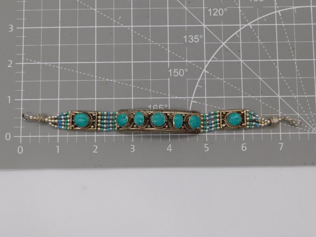 Jewelry Tibetan Silver Turquoise Cabochon Bracelet: A silver-tone link bracelet featuring five round turquoise cabochons set along a beaded and filigree band, finished with a lobster clasp. Measures approximately 7 inches in length, shown on a gridded