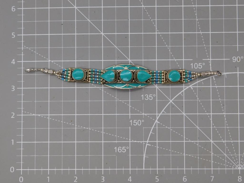 Turquoise Inlay Panel Bracelet, Tibetan Style: An ornate silver-tone link bracelet featuring a central oval panel set with three turquoise teardrop and round cabochons, flanked by additional round turquoise stones and rows of tiny blue seed