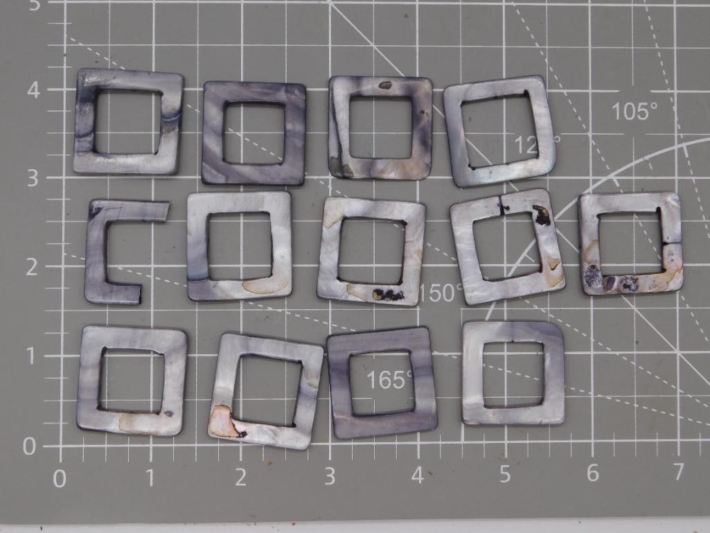Mother of Pearl Square Pendant Blank Lot: Set of thirteen square open-center mother-of-pearl pendant blanks with iridescent gray-purple shell finish, each roughly 1 inch, shown on a ruled mat. Total weight labeled 46 grams. Part of the 2026