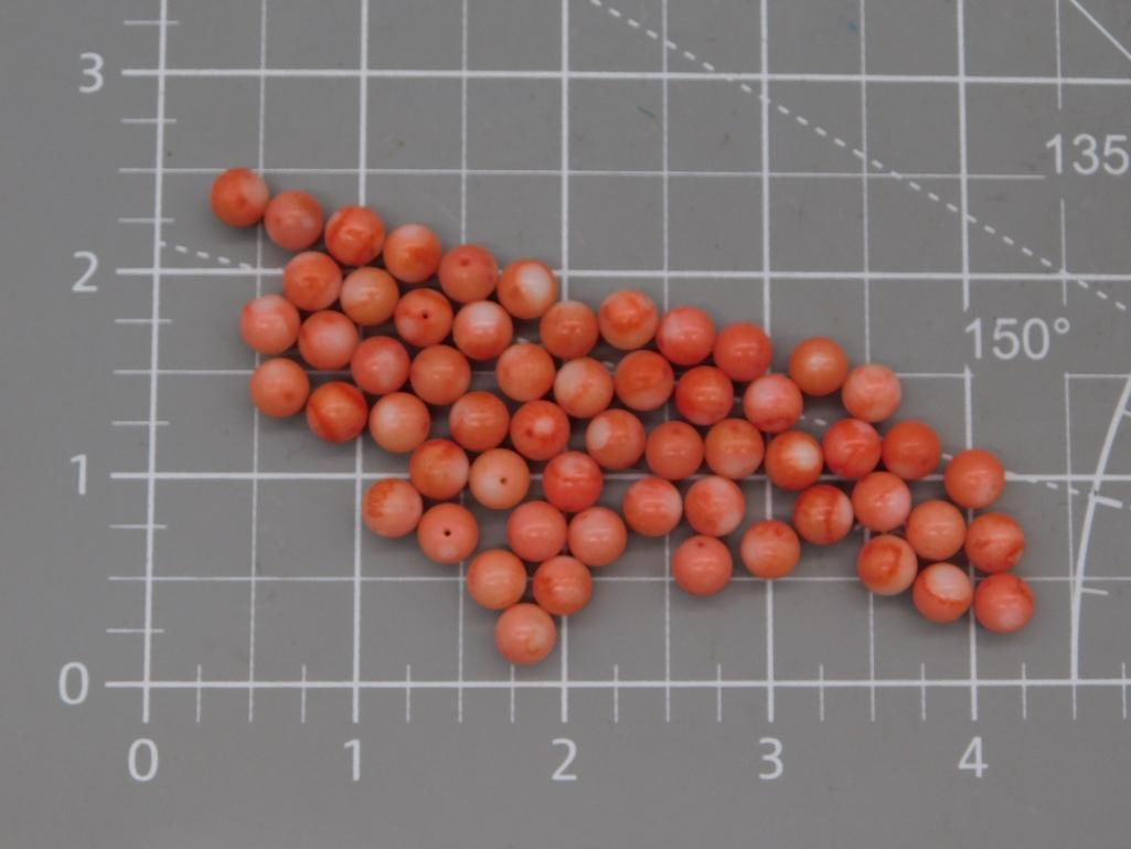 Coral-Style Round Bead Lot: Large lot of round orange-red coral-style beads, each approximately 7mm, shown on a ruled mat. Total weight labeled 33 grams. Part of the 2026 Rock Auction.