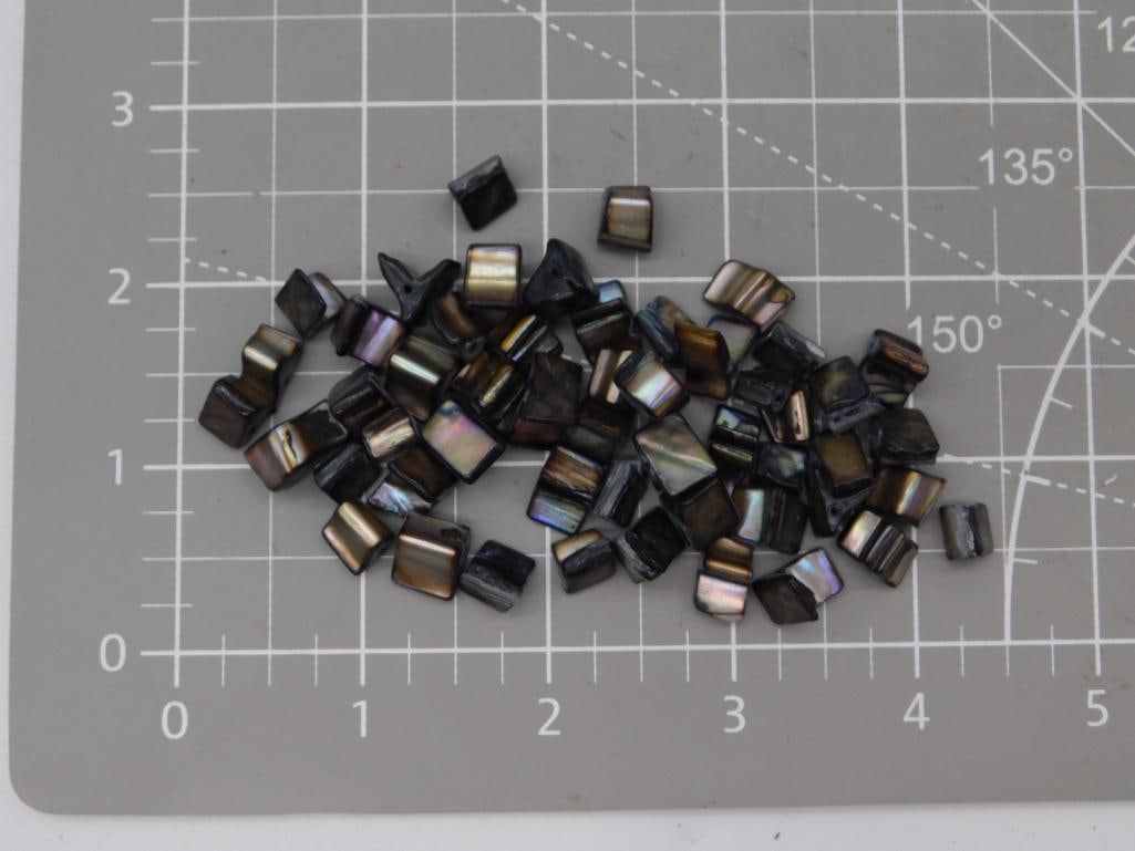 Abalone Shell Chip Bead Lot: Large lot of irregular dark iridescent abalone/mother-of-pearl shell chip beads showing purple, green, and gold flash, each approximately 8mm, shown on a ruled mat. Total weight labeled 36 grams.