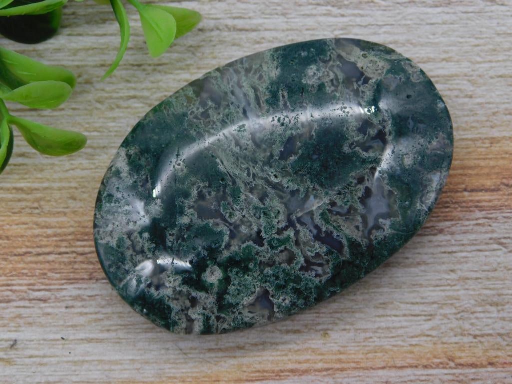 Moss Agate Palm Stone - Polished Green Freeform Crystal: A polished moss agate palm stone in dark green and gray dendritic patterns, oval freeform shape with a high glassy polish. Measures roughly 2.5 inches across, shown beside a 1966 Washington quarter fo