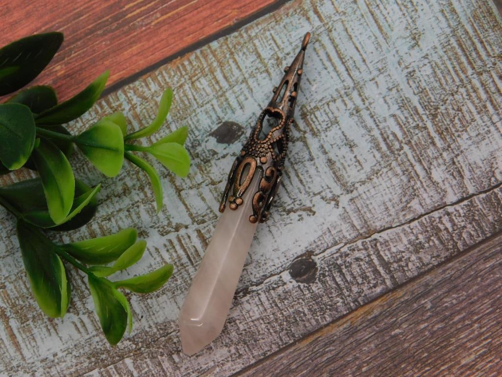 Rose Quartz Crystal Point Pendant with Ornate Bronze-Tone Cap: A faceted rose quartz crystal point pendant capped with an ornate bronze filigree bail featuring scrollwork and bead detailing. Measures roughly 3 inches long, shown beside a 1966 Washington quarter
