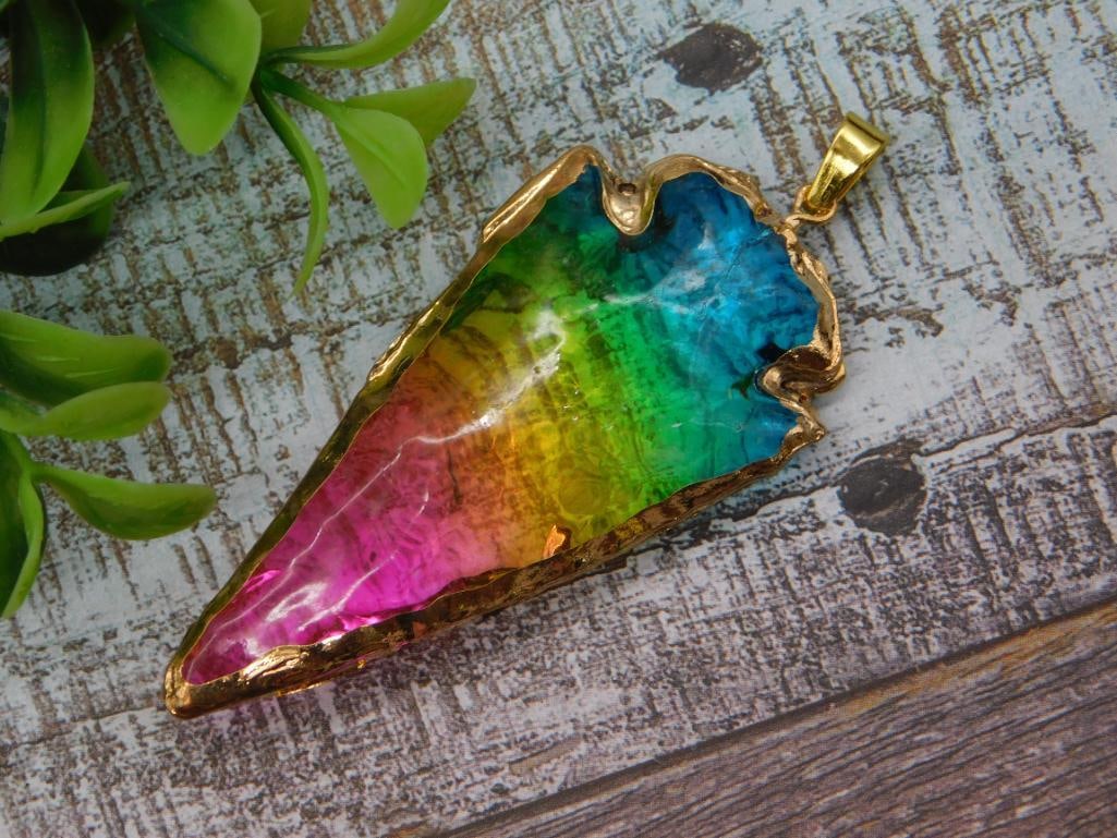 Titanium Aura Quartz Slice Pendant in Gold-Tone Bezel: Freeform polished stone slice pendant displaying vivid rainbow titanium-aura coloring in pink, orange, yellow, green, and blue, edged in a raw gold-tone electroplated bezel with bail. A US quarter is