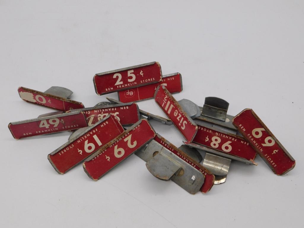 Ben Franklin Stores Vintage Price Tag Clip Lot: Group of approximately a dozen red and cream metal price tag holders/clips marked "BEN FRANKLIN STORES" with various embossed prices (19c, 25c, 29c, 49c, 69c, 98c) and a size tag. Ruler in photo 2 sho