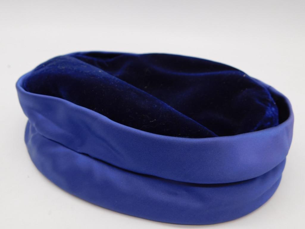 Antique Blue Satin and Velvet Pillbox Hat - Junior B: A vintage royal blue satin pillbox-style hat with dark blue velvet crown, interior lined in tan fabric. The inner label is embroidered "Junior B" with a bee motif in red and black thread. Measures app
