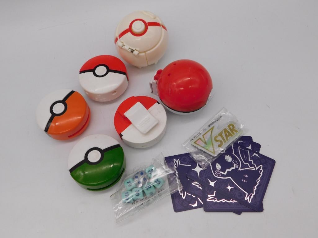 Pokemon Poke Ball Toy Lot with Dice and Anime Trading Cards: A group lot including six plastic Pokemon-themed poke ball toys/containers in red, white, orange, green, and cream, a small bag of dice, and a set of holographic Japanese/anime style trading cards