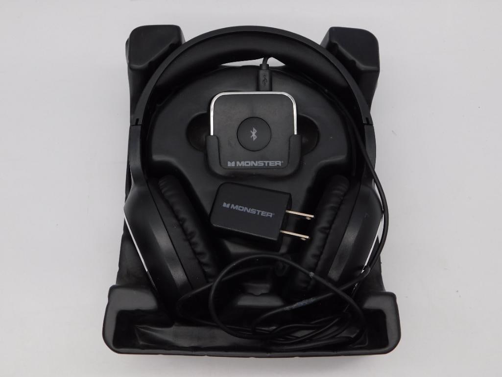 Monster Bluetooth Over-Ear Headphones with Charging Dock: A pair of black Monster brand Bluetooth wireless headphones housed in a fitted charging/storage tray, with a Monster Bluetooth receiver module and Monster USB wall charger plug included. Tray