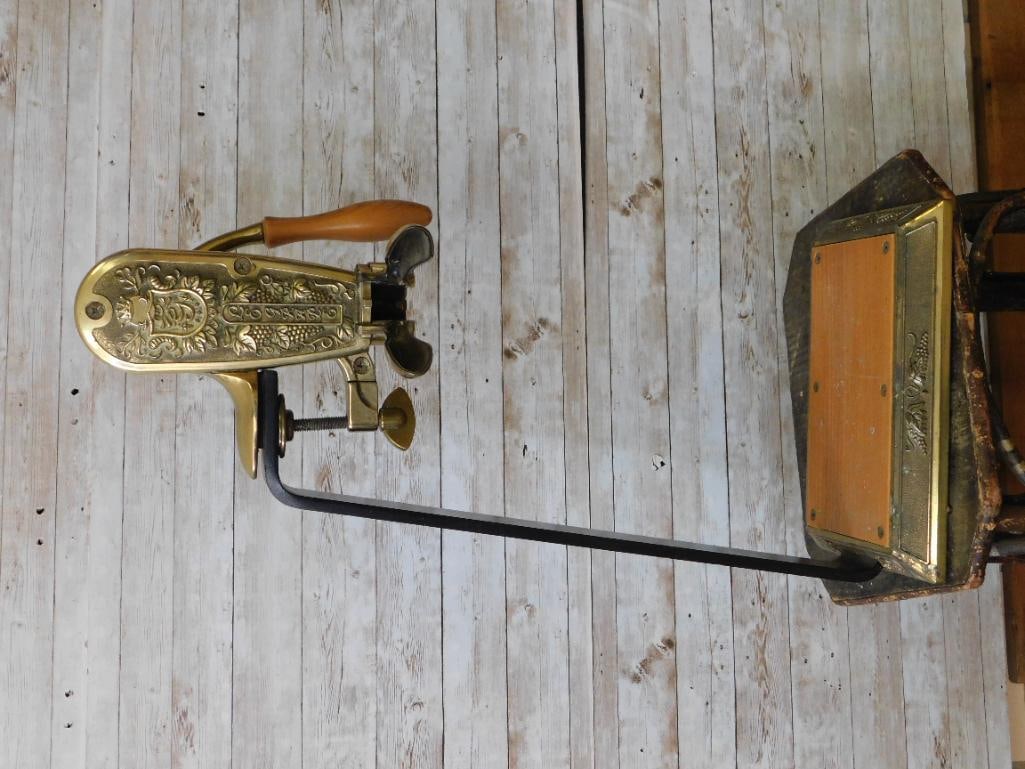 Antique Brass Grape-Motif Wine Bottle Corker / Capping Press with Wood Handle: An ornate brass mechanical press decorated with grape and vine relief motifs, featuring a turned wood handle, hinged clamp arm, and a wood-inlaid brass base plate, likely used as an antique wine