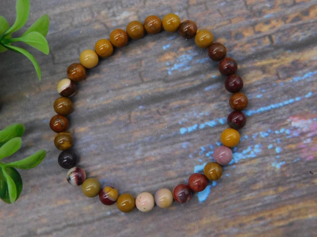 Gemstone Beaded Stretch Bracelet - Mookaite Jasper: A stretch bracelet strung with round polished mookaite jasper beads in variegated tones of rust, gold, mustard, cream, and burgundy. Beads measure approximately 8mm each; a US quarter is shown for