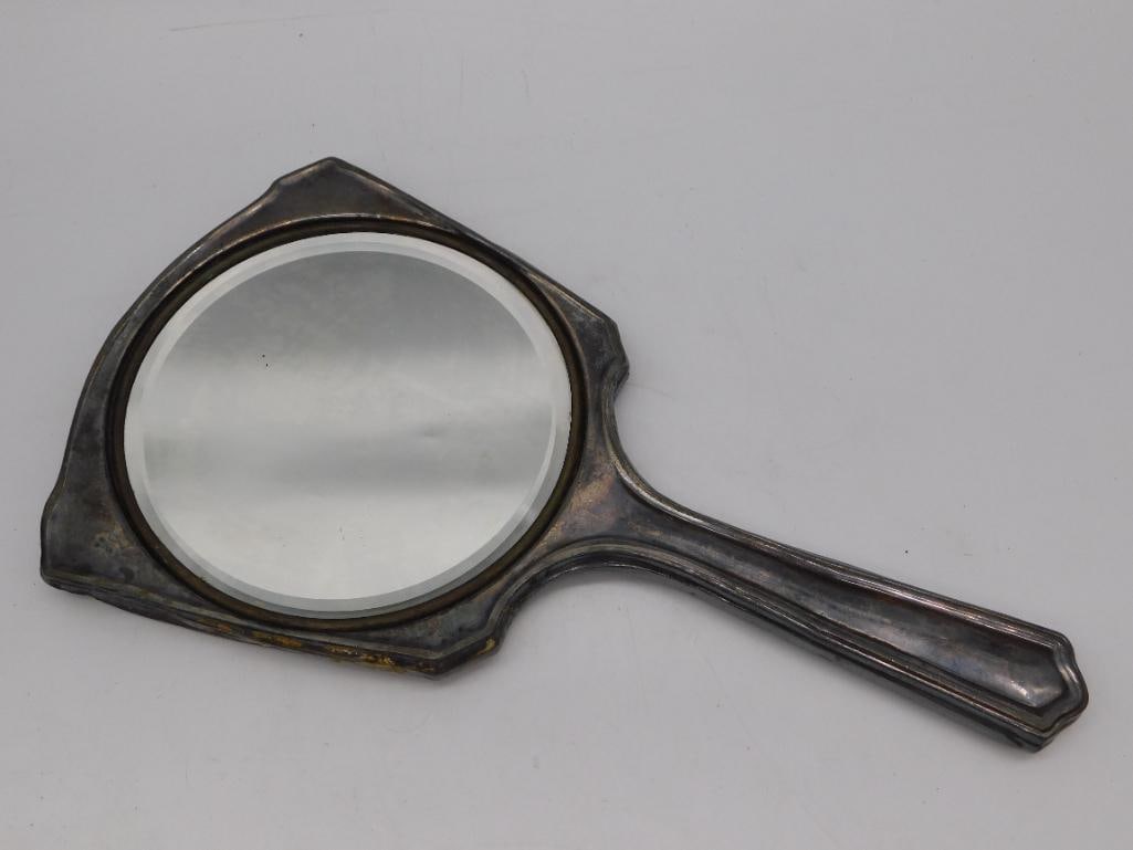 Antique Silver-Plate Hand Mirror with Engraved Cartouche: Silver-plate vanity hand mirror with a shield-shaped beveled glass face bordered by a decorative rim, reverse side featuring a hammered/textured finish surrounding a blank engraved cartouche for