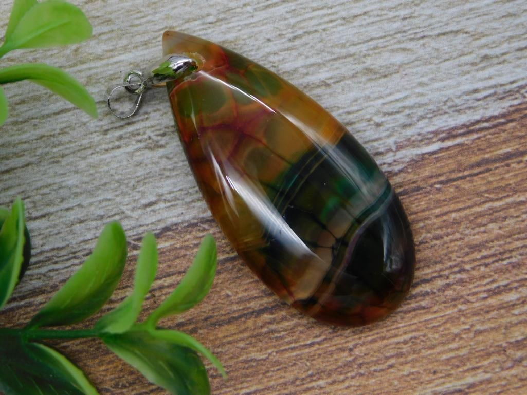 Agate Pendant - Polished Multicolor Teardrop Stone Necklace Drop: A teardrop-shaped polished agate pendant displaying rich banded coloring of amber, forest green, and deep red/black, with a silver-tone bail for stringing. Shown beside a 1966 Liberty quarter for