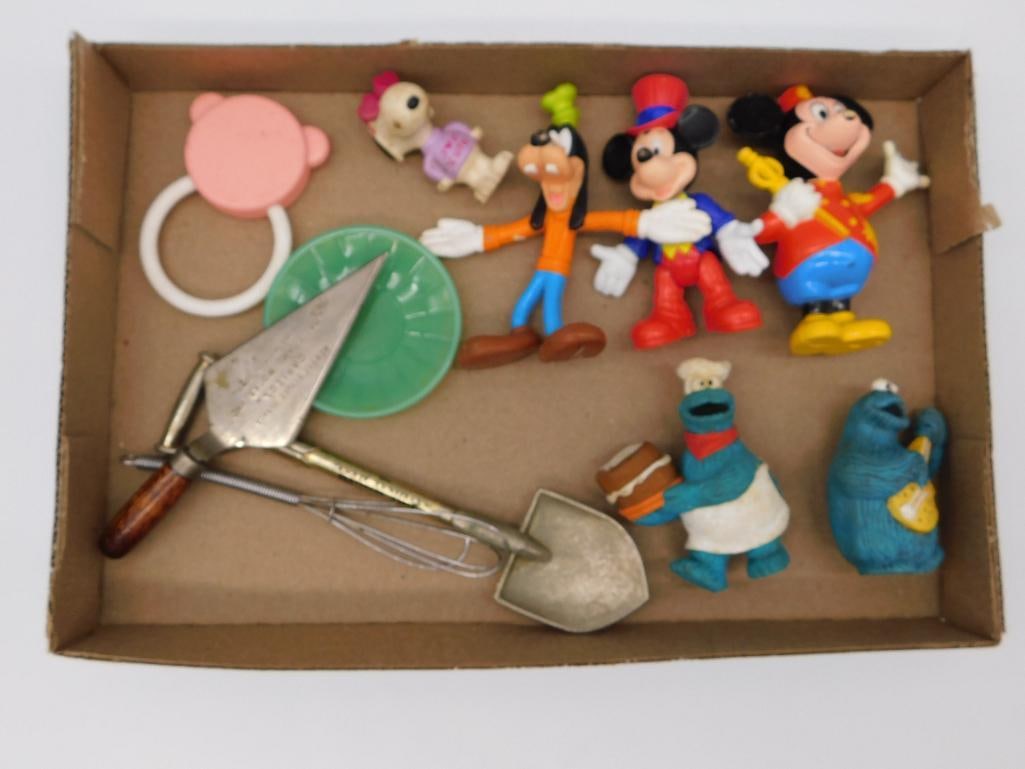 Toy Lot - Vintage Disney and Sesame Street PVC Figures with Kitchen Tools: A cardboard flat holding a mixed lot of vintage plastic/PVC figures including Goofy, Mickey Mouse, Minnie Mouse, Cookie Monster (baker version), and a blue Grover-like Sesame Street figure, plus a sma