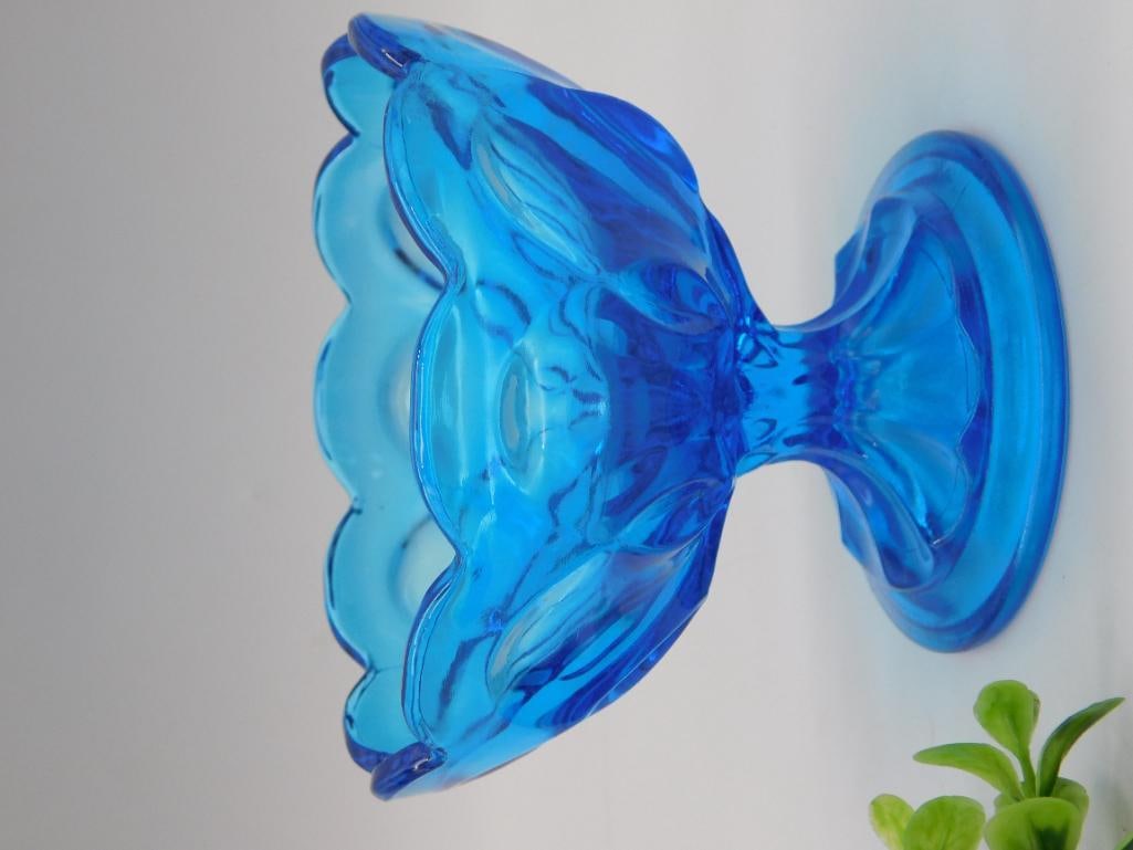 Art Glass - Blue Depression-Style Glass Compote Candle Holder: A vivid cobalt/turquoise blue pressed glass compote or candle holder with a scalloped, petal-form bowl atop a flared trumpet base, in the depression glass style. A close-up photo shows mold seam