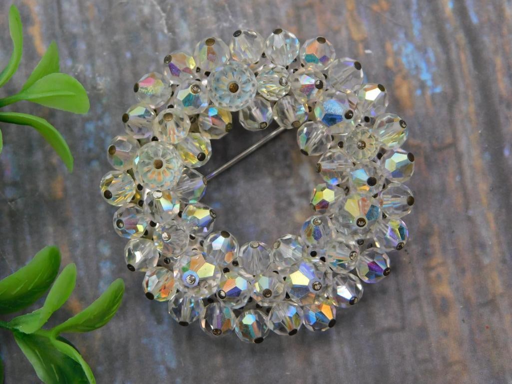 Jewelry - Two Aurora Borealis Crystal Rhinestone Wreath Brooches: A pair of vintage costume jewelry brooches, each formed as a circular wreath of faceted aurora borealis crystal beads: one set in an open silver-tone filigree frame, the other a simpler beaded wreath