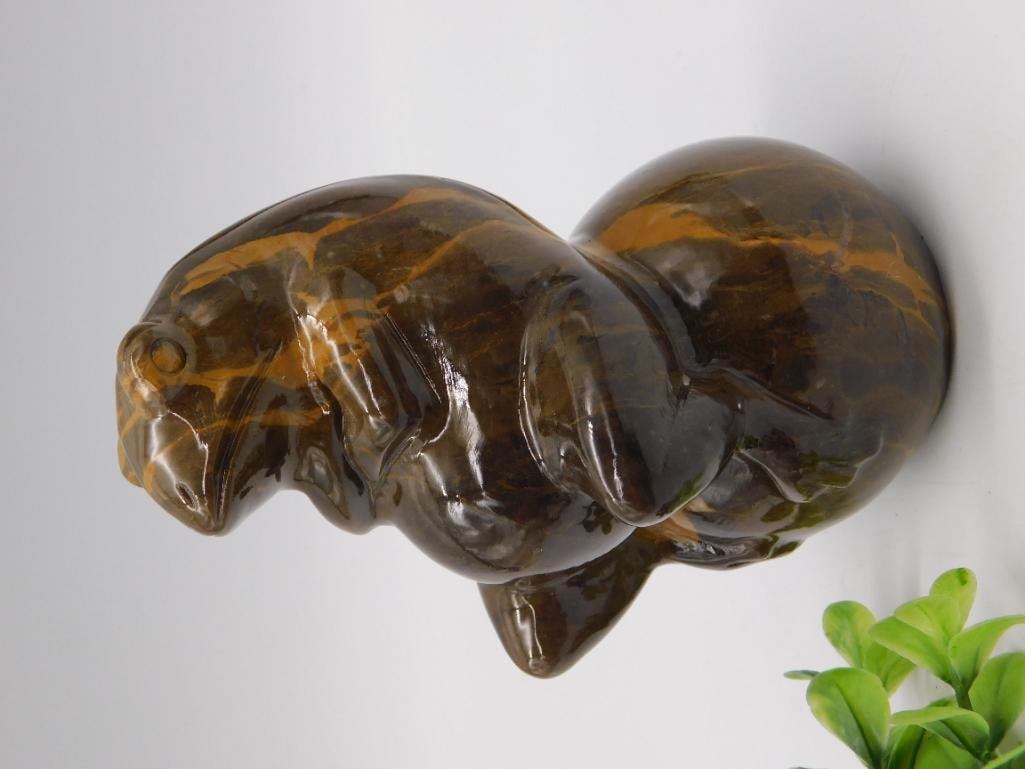 Tiger's Eye Carved Stone Otter Figurine: Polished tiger's eye carving of a curled otter or seal figure, showing the stone's characteristic golden-brown chatoyant banding throughout. Measures approximately 4-5 inches long as shown against a r