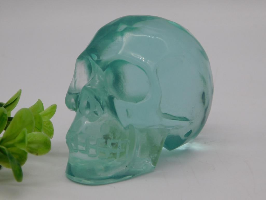 Carved Aqua Glass Skull: Translucent aqua-green carved glass skull with detailed eye sockets and teeth, catching light throughout the piece. Measures approximately 3 inches as shown against a ruler; original lot tag notes