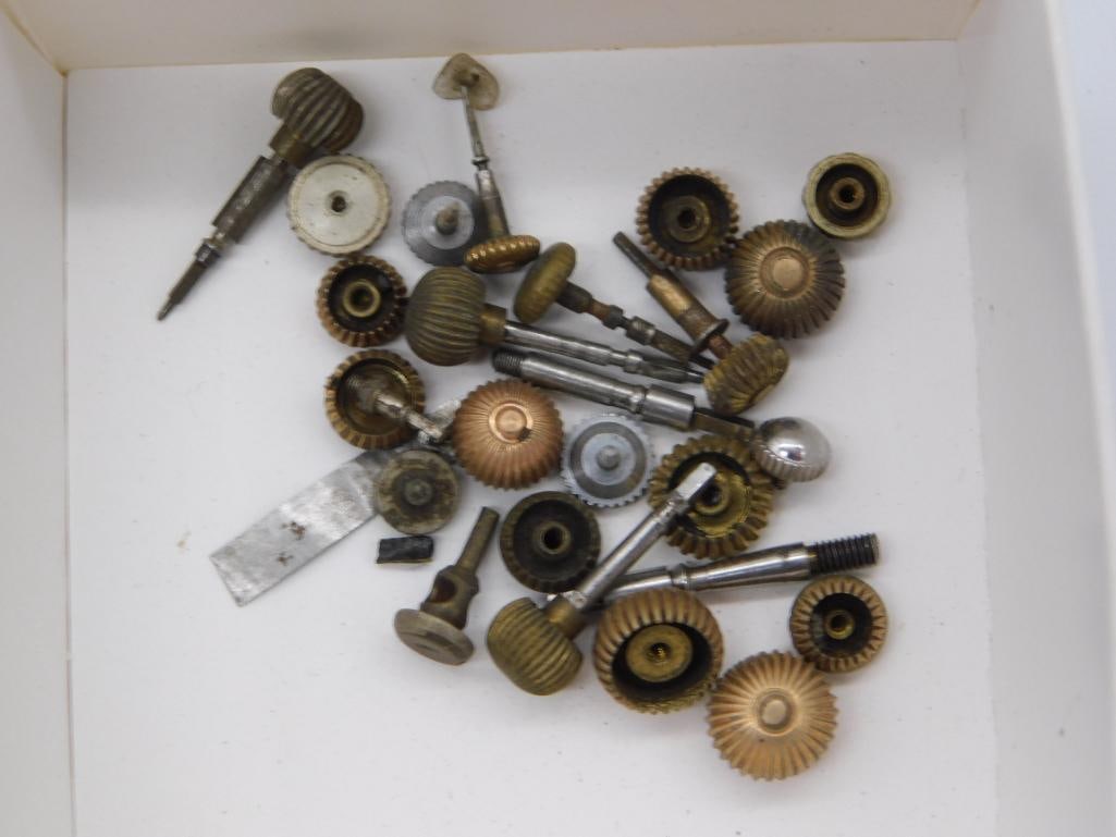 Antique Watchmaker Gear and Pinion Assortment, Boxed: A cardboard box containing a large mixed assortment of small brass gears, pinions, fluted knobs, and steel shafts used in clock or watch repair. A quarter shown alongside the box gives scale to the