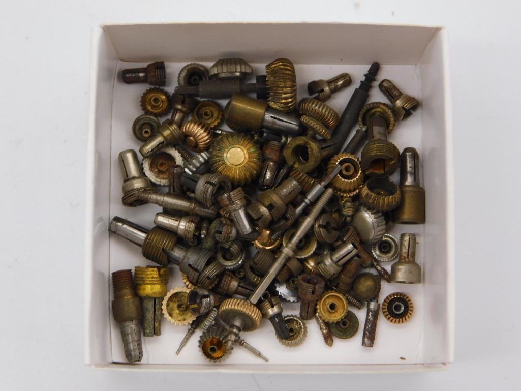 Antique Watchmaker Gear and Pinion Parts Lot, Boxed: A cardboard box filled with a mixed assortment of small brass and steel gears, fluted knobs, and pinion shafts salvaged for watch and clock repair. Pieces range from tiny fractional-inch gears to