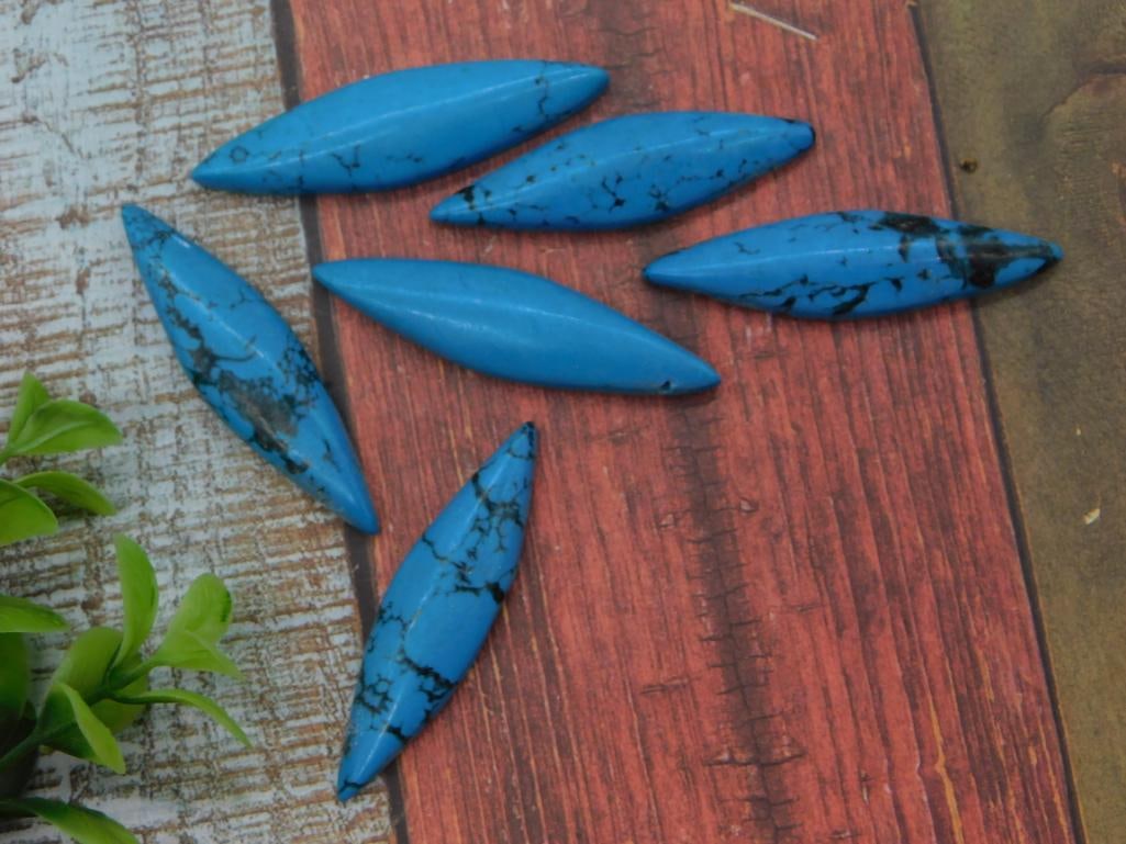 Blue Turquoise-Style Navette Cabochon Beads, Lot of 6: Six loose navette (marquise-shaped) cabochons in vivid blue with black matrix veining, consistent with dyed howlite/magnesite turquoise. Each bead measures approximately 1.5 inches long, shown with a