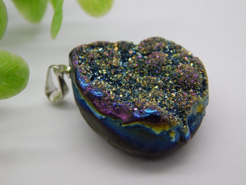 Rainbow Titanium Druzy Quartz Pendant, Silver Bail: Druzy quartz pendant coated in rainbow titanium finish, displaying iridescent blue, purple, and gold sparkle crystals with a simple silver-tone bail. Measures approximately 1.5 inches, shown beside a