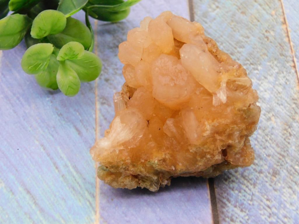 Natural Calcite Mineral Cluster: A honey-orange calcite crystal cluster with a druzy, terraced crystal formation atop a rough matrix base. Shown next to a quarter for scale, roughly 2-3 inches across.