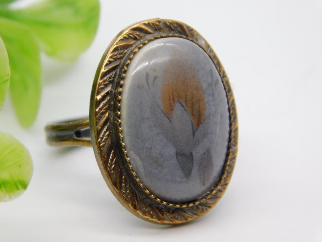 Antique Agate Cabochon Adjustable Ring: An antique brass-tone adjustable ring set with an oval banded agate/jasper cabochon in gray and rust tones, with engraved leaf-motif bezel.