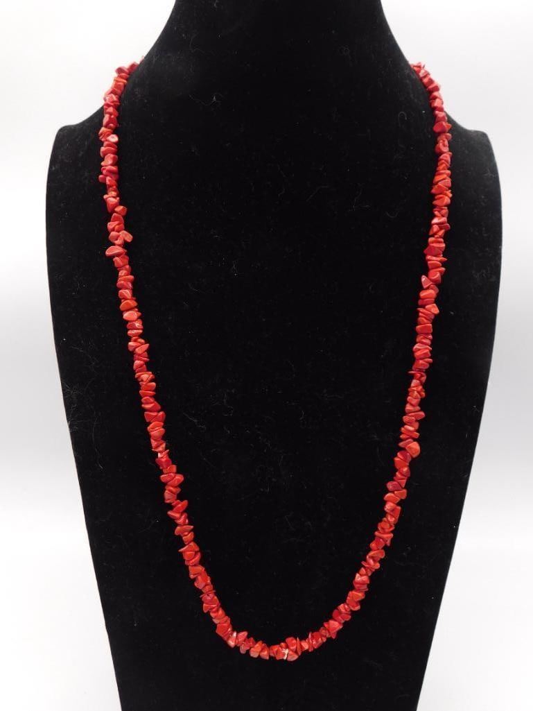 Red Coral Chip Bead Strand Necklace: Single continuous strand necklace of irregular natural red coral chip beads in deep red-orange tones. Slip-over style with no clasp. Approximately 26-28 inches in length.