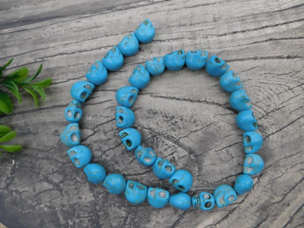 Turquoise Blue Howlite Skull Bead Necklace: Strand of carved turquoise-blue howlite skull-shaped beads strung as a necklace.