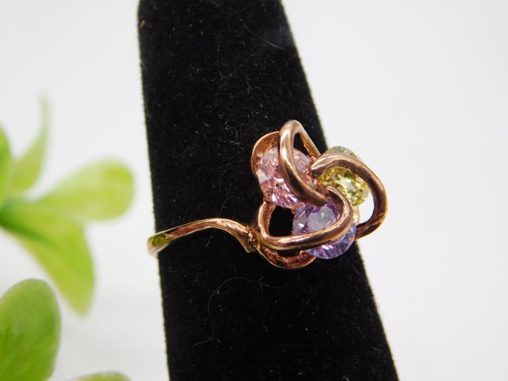 Gold-Tone Ring with Pink and Purple Stone Cluster Size 7: A rose gold-tone ring featuring a cluster of pink lavender and yellow-green faceted stones in a swirled setting. Marked size 7.