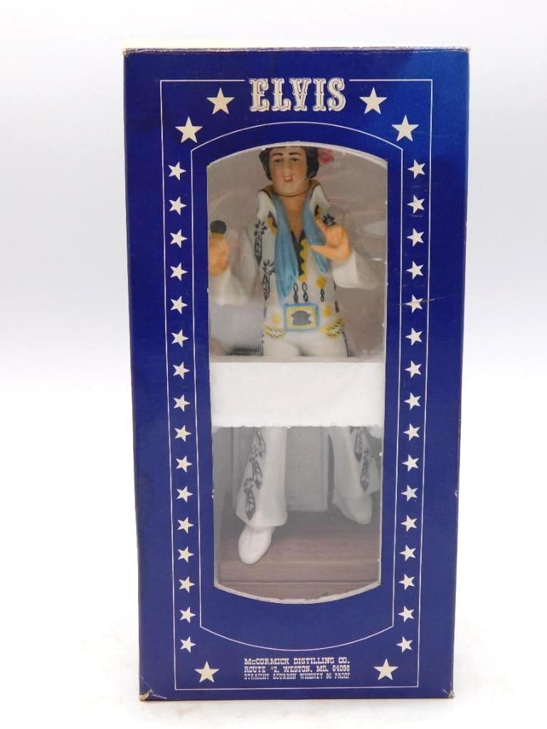 McCormick Elvis Presley No. 3 Music Box: A McCormick Distilling Co. decanter modeled as Elvis Presley in a fringed jumpsuit, mounted upon a wood-grained music-box base. Third in the series and complete in its original blue starred box. The