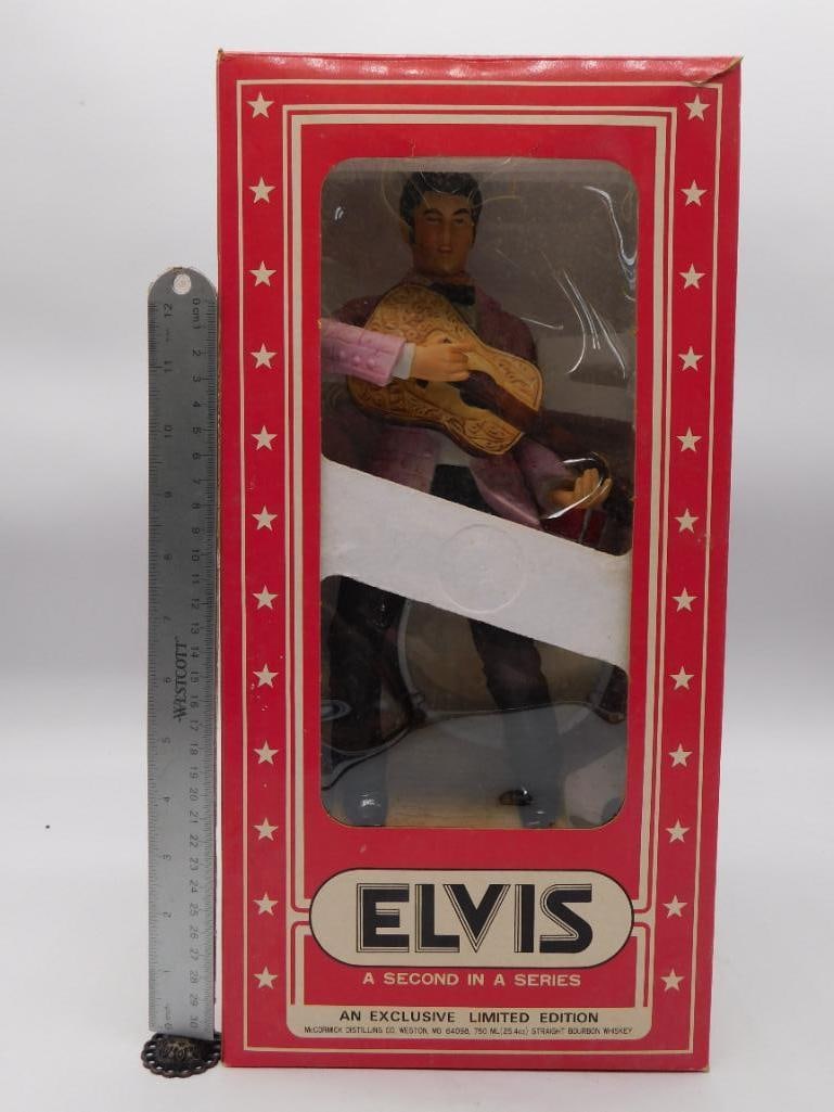 McCormick Elvis Presley Yours Elvis '55: A McCormick Distilling Co. decanter sculpted as Elvis Presley performing with guitar and drum, the base signed "Yours Elvis '55." Ceramic construction with the gold foil McCormick label still in