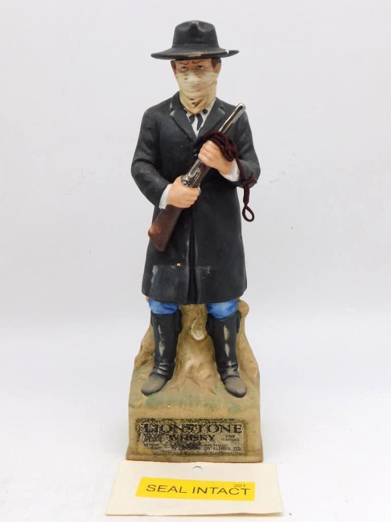 Lionstone Western Masked Bandit with: A commanding Lionstone decanter modeled as a masked road agent in a long black coat, a kerchief drawn over his face and a shotgun held across his chest. The bisque finish and restrained painting give 
