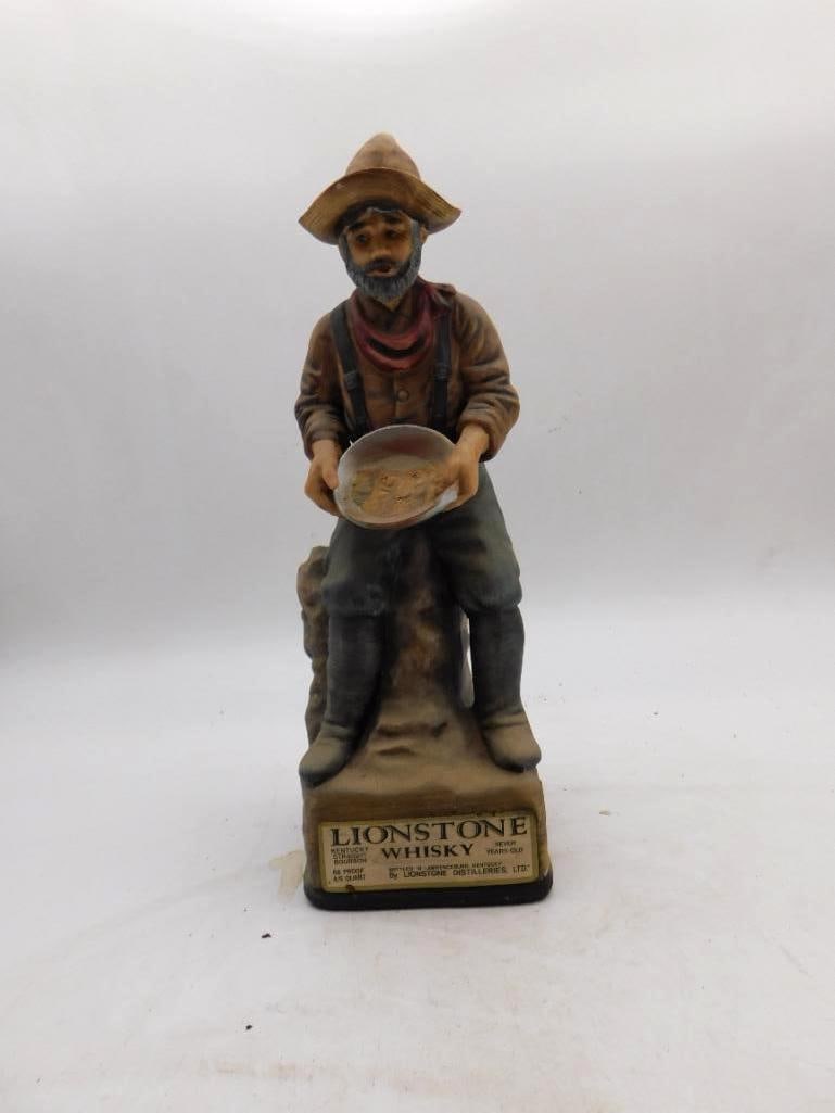 Lionstone Gold Panner 1862-1868 Old West: A genial Lionstone decanter modeled as a bearded prospector seated on a stump, his pan tipped forward to show the color he has raised. The straw hat, braces and creased boots are all rendered with a