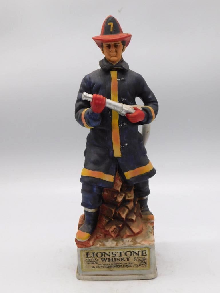 Lionstone The Firefighter Decanter: A Lionstone Kentucky Straight Bourbon Whiskey decanter titled "The Firefighter," modeled as a fireman in turnout gear with his hose, standing on a brick-form base with a descriptive plaque. A resolute