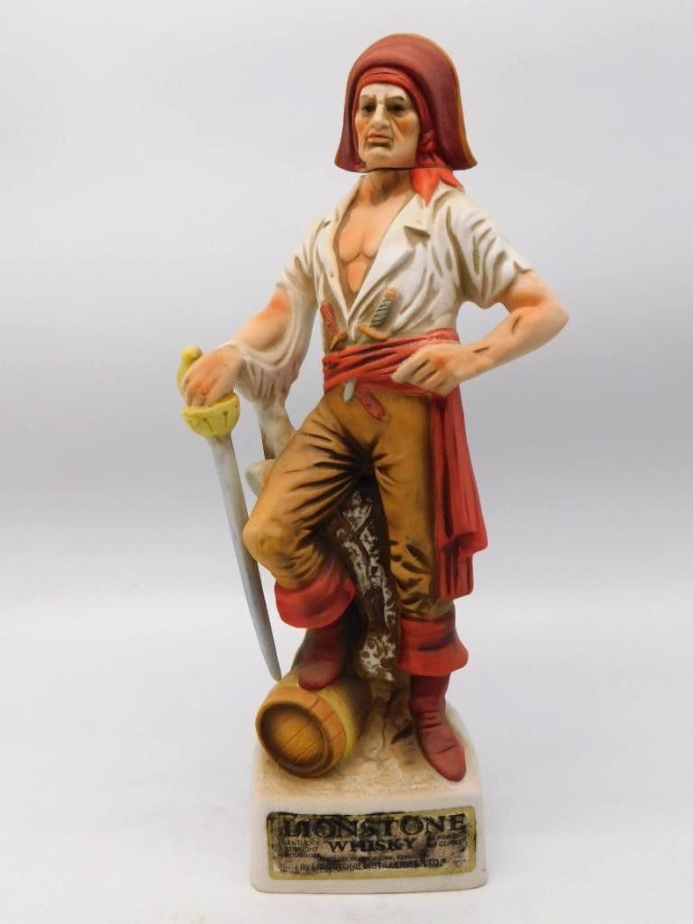 Lionstone Buccaneer Bisque Porcelain: A stout Lionstone decanter modeled as a buccaneer standing at his ease, cutlass point set against a powder keg and a red sash knotted at the waist. The sculptor gave him a weathered, sober face, and