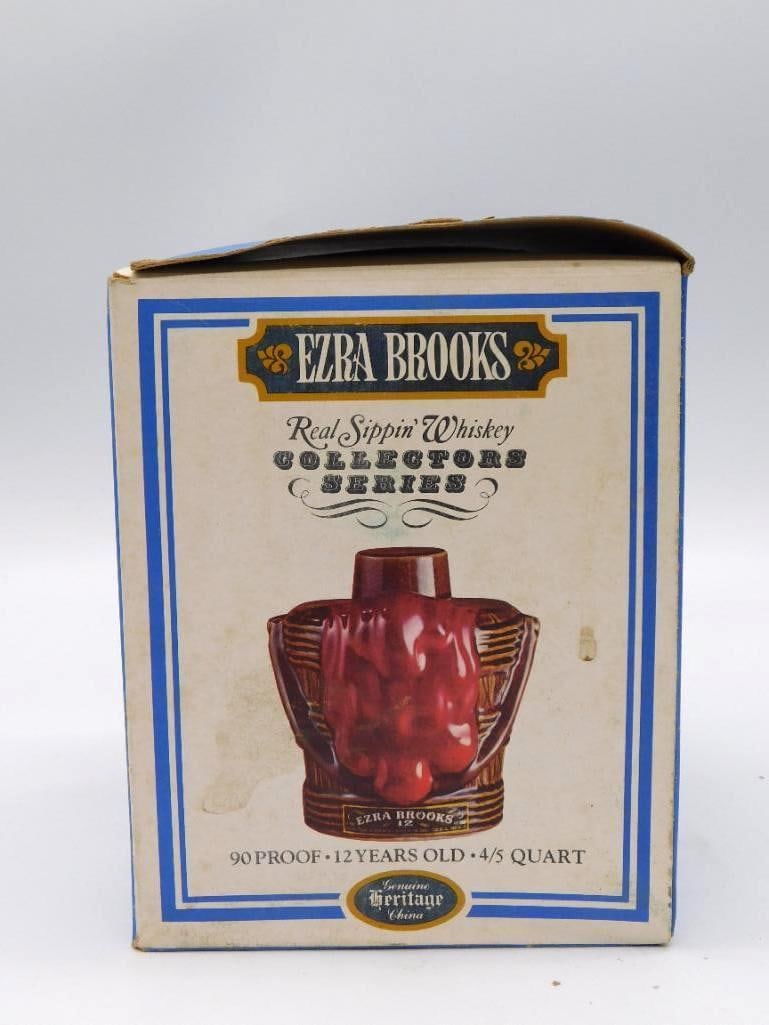 Ezra Brooks Curtain and Bucket of Blood: Two vintage whiskey decanters offered together. The first is an Ezra Brooks 12-Year Collectors Series bottle cast with an abstract draped-curtain design in brown and red glaze, complete with its