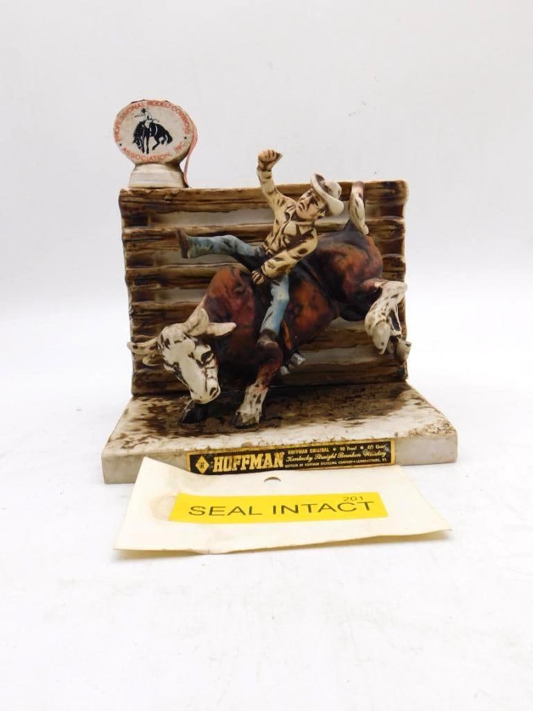Hoffman Rodeo Cowboys Association Bull: A Hoffman decanter cast with a bull rider in mid-buck against a rail fence, one arm flung high and the brahma twisting beneath him. The modeling is lively and the earthen browns nicely handled, the