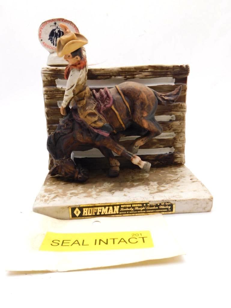 Hoffman Saddle Bronc Riding Rodeo: A spirited Hoffman decanter modeled as a saddle bronc rider hard at work against a corral rail, the horse pitching and the cowboy's hat flying, a Professional Rodeo Cowboys Association plaque set