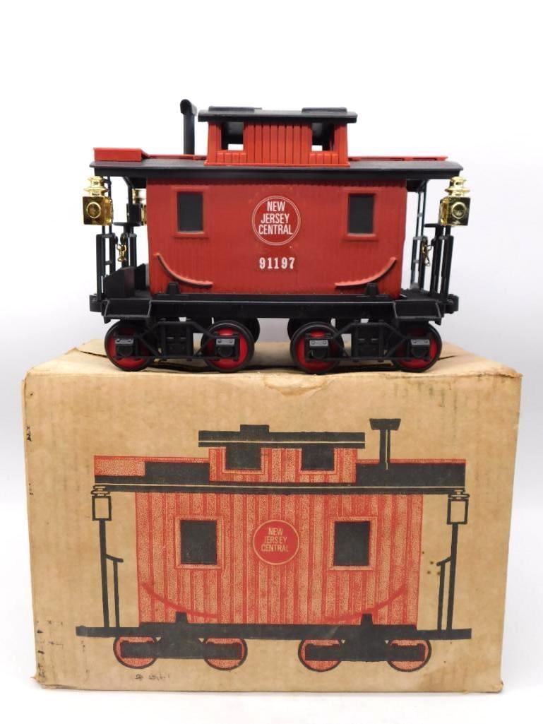 New Jersey Central Caboose 91197: A decanter built as a New Jersey Central caboose, number 91197, in barn red with a black roof, brass marker lamps at the corners and red spoked wheels on a full black underframe. A stout, particular m