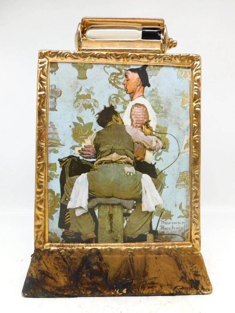 Norman Rockwell The Tattooist Ltd Ed: A singular ceramic decanter cast as a gilt picture frame holding Norman Rockwell's Saturday Evening Post painting The Tattooist, wherein a sailor sits patient while yet another sweetheart's name is in