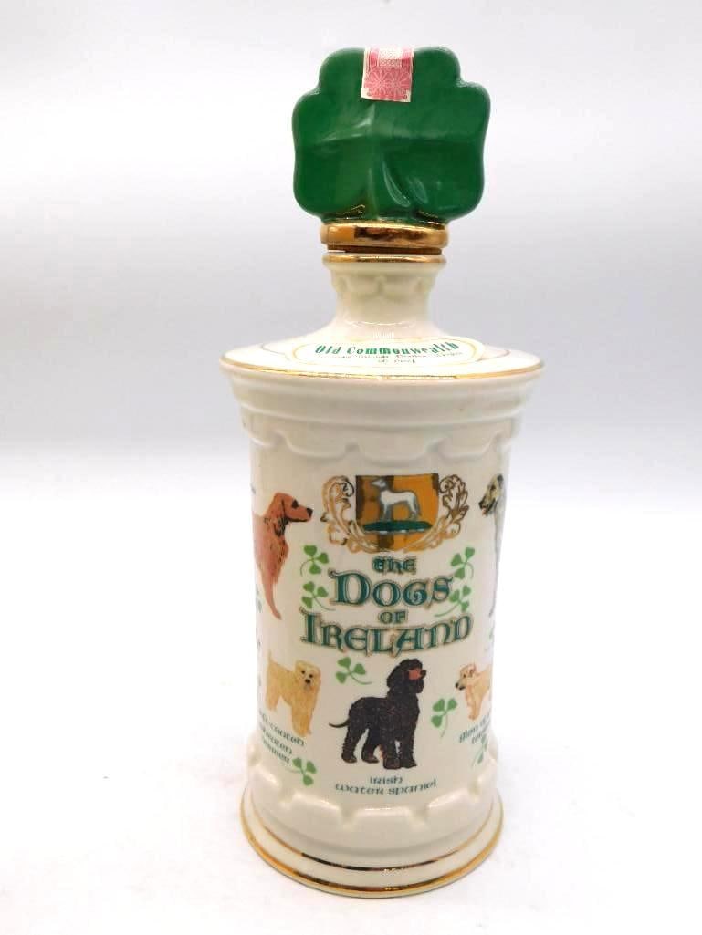 RARE Old Commonwealth Dogs of Ireland: An Old Commonwealth hand-decorated porcelain decanter, The Dogs of Ireland, painted with Irish breeds about the body. The green shamrock stopper carries an intact tax stamp. It comes with the original