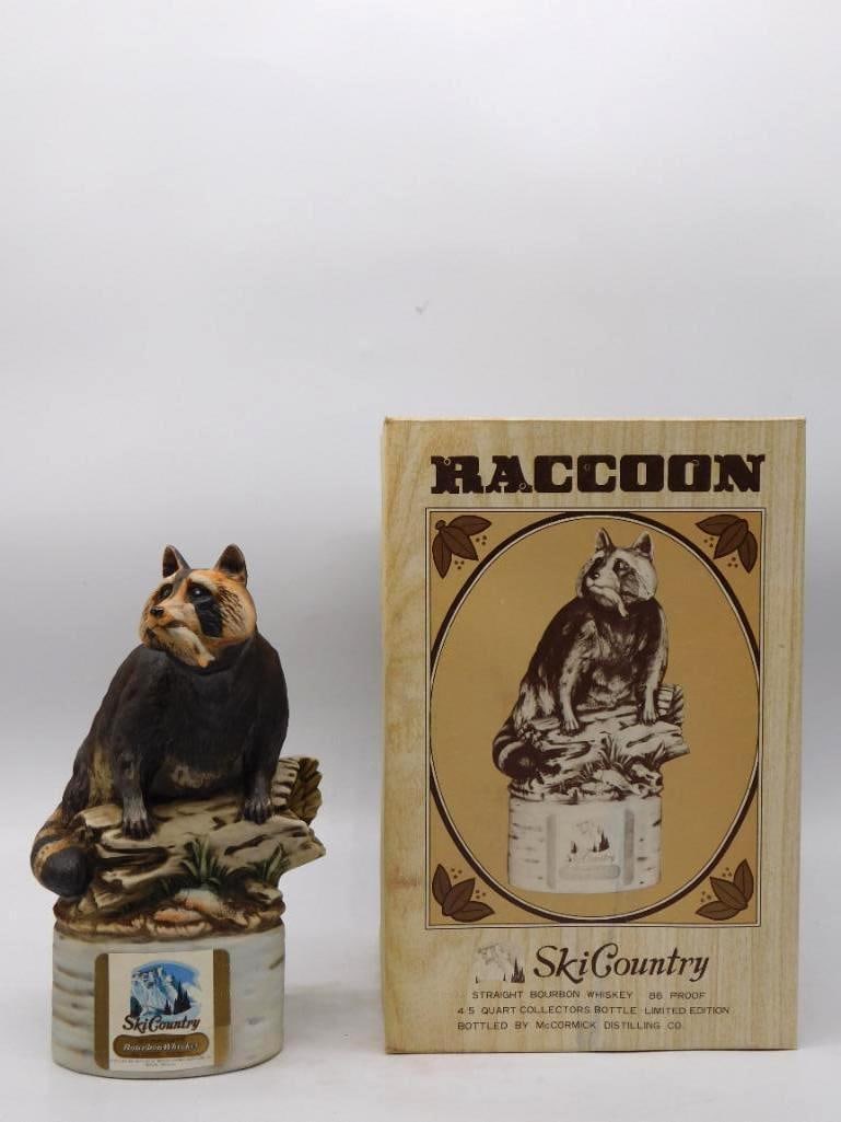 Ski Country Raccoon Wildlife Decanter: A capital Ski Country decanter sculpted as a raccoon seated upon a fallen birch, one paw drawn up and the masked face turned to the viewer. The modeling of the fur is uncommonly fine and the ringed